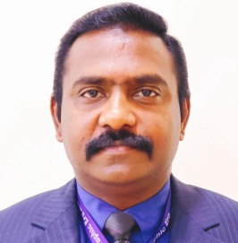 Professional headshot of a man with a mustache wearing a purple suit, blue shirt, and tie, facing the camera.